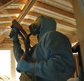 Technician applying spray foam insulation in a new construction building.