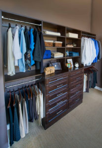 Organized walk-in closet with custom shelving and drawers.